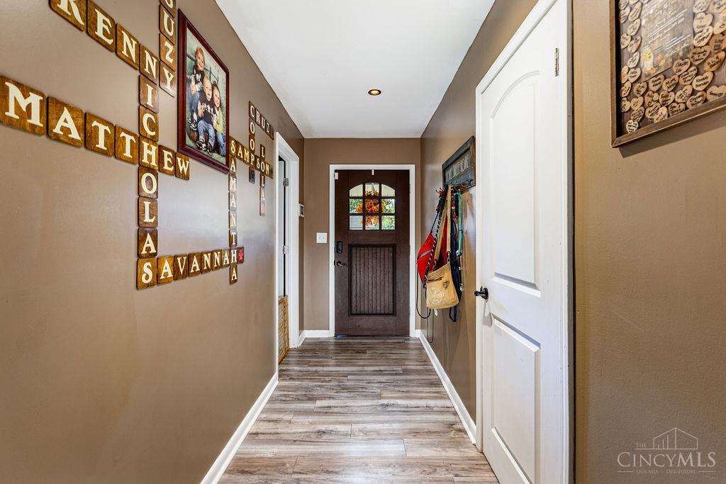 Entry hallway with personalized name tiles, wood-look flooring, and a dark wood door with glass panes.