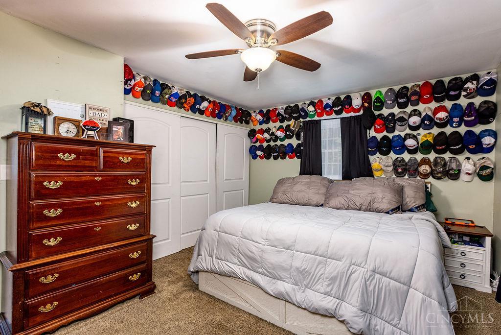 Bedroom with a white bed and baseball caps displayed in rows along the walls.