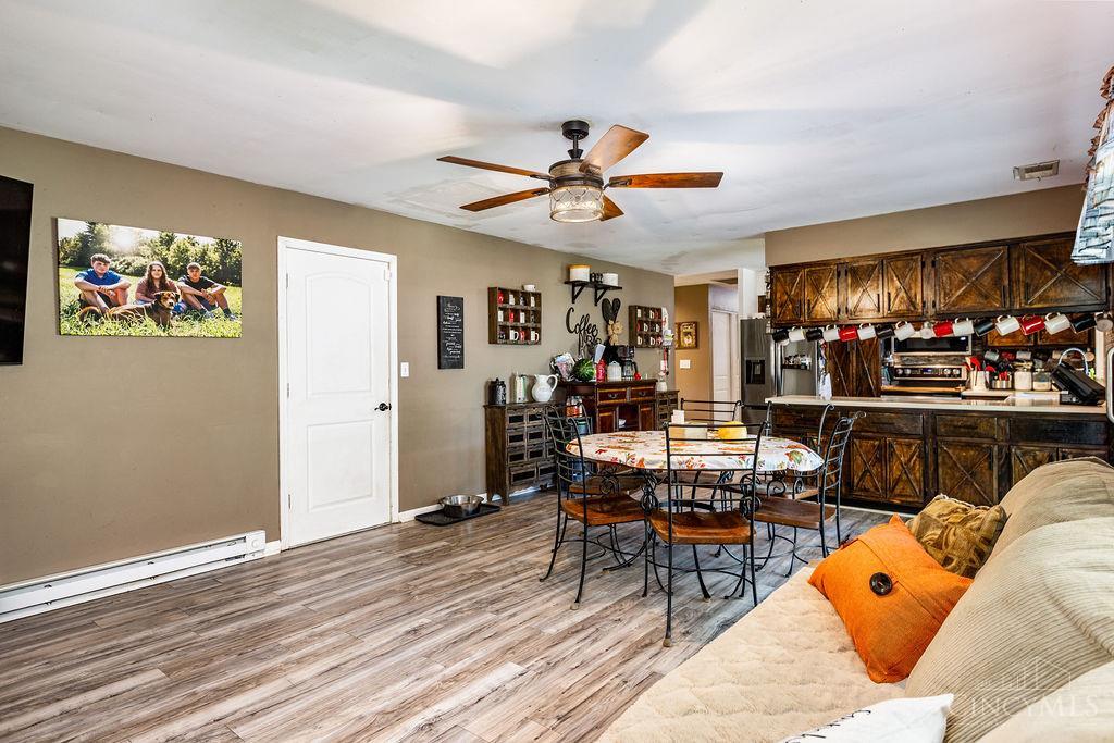 Open-plan kitchen and dining area with dark wood cabinets, a round table, and a sofa with orange cushions.