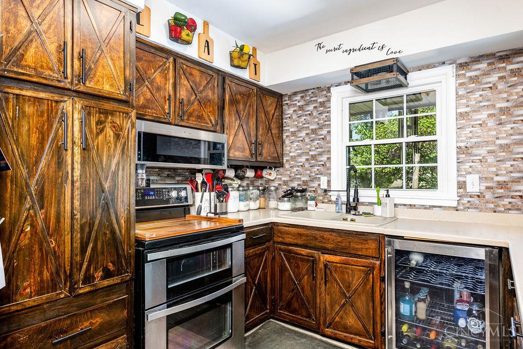 Kitchen with rustic X-pattern wood cabinets, stainless appliances, mosaic backsplash, and a window above the sink.