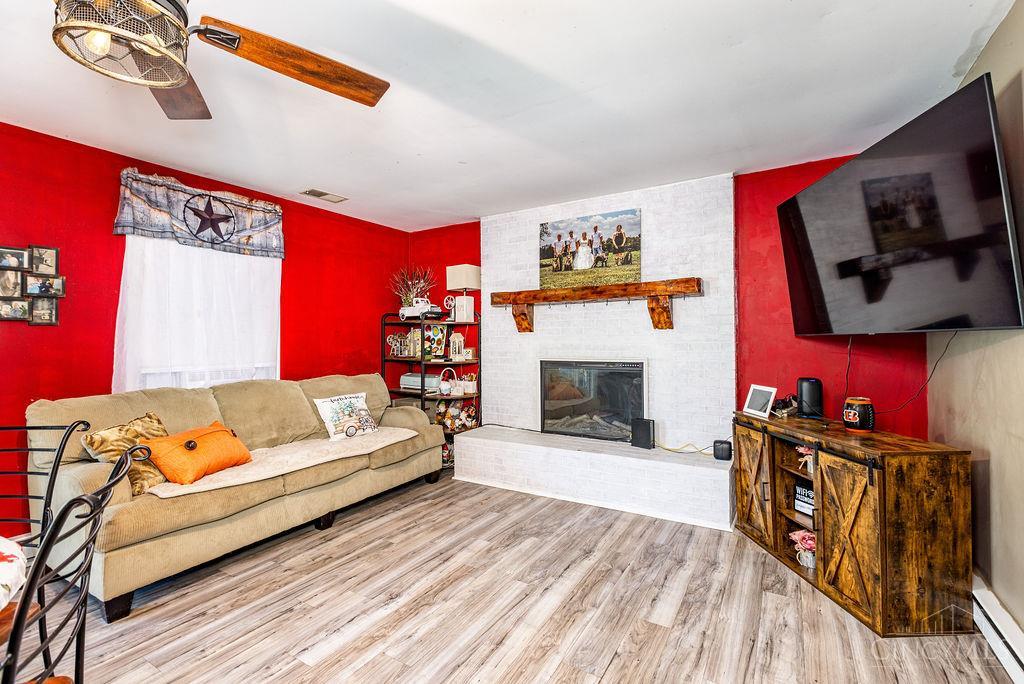 Living room with red walls, white brick fireplace, beige sofa, and wall-mounted TV.