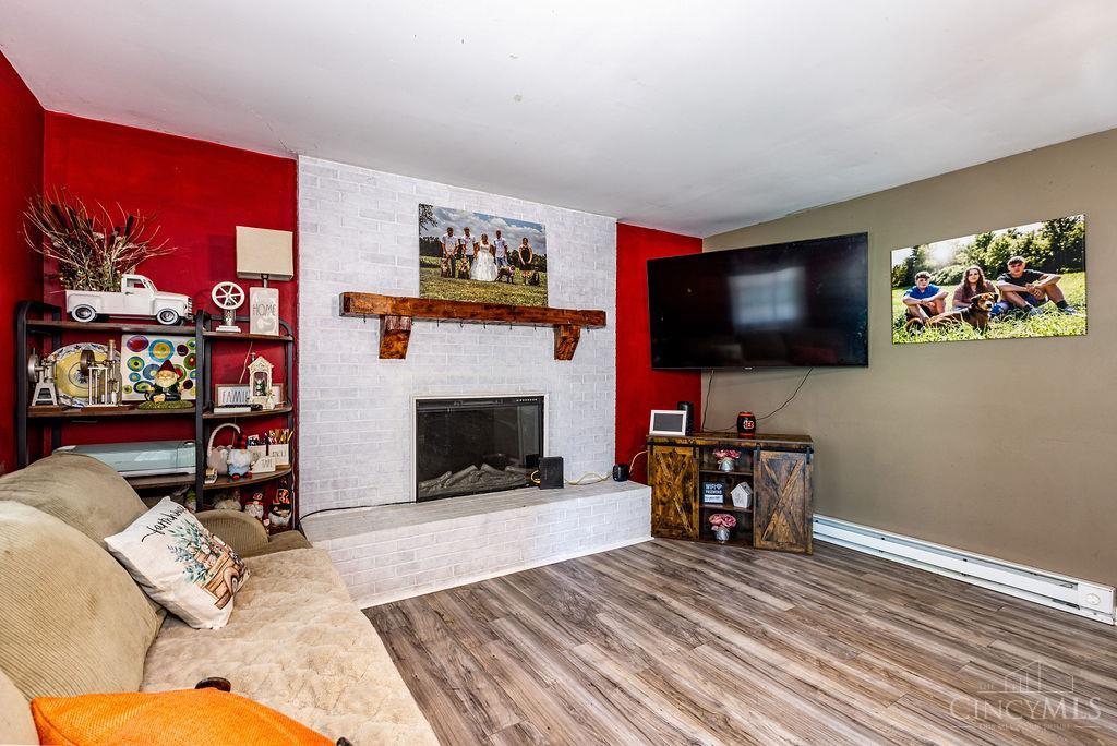 Living room with a white brick fireplace, red accent walls, and wall-mounted television.