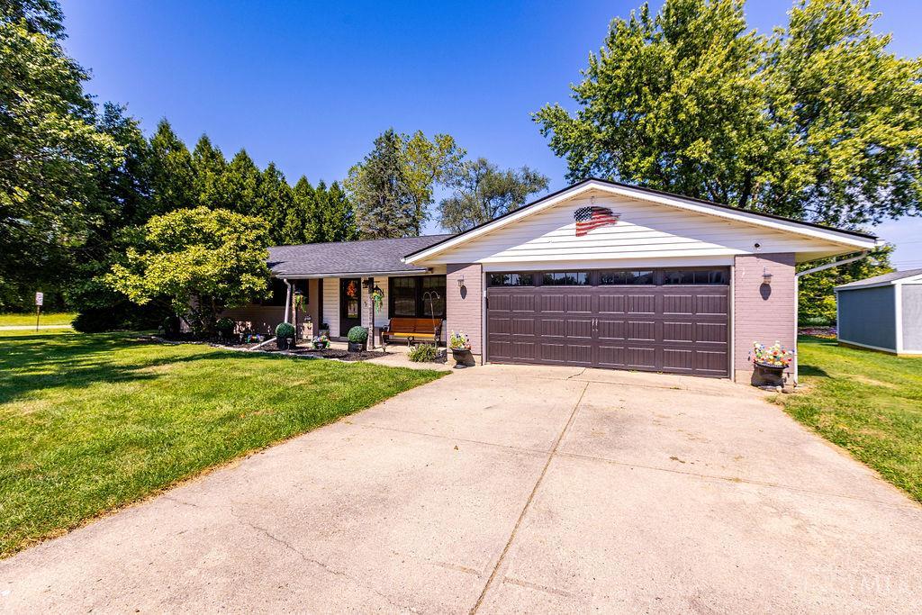 Single-story home with a wide double garage, covered porch, and broad concrete driveway.