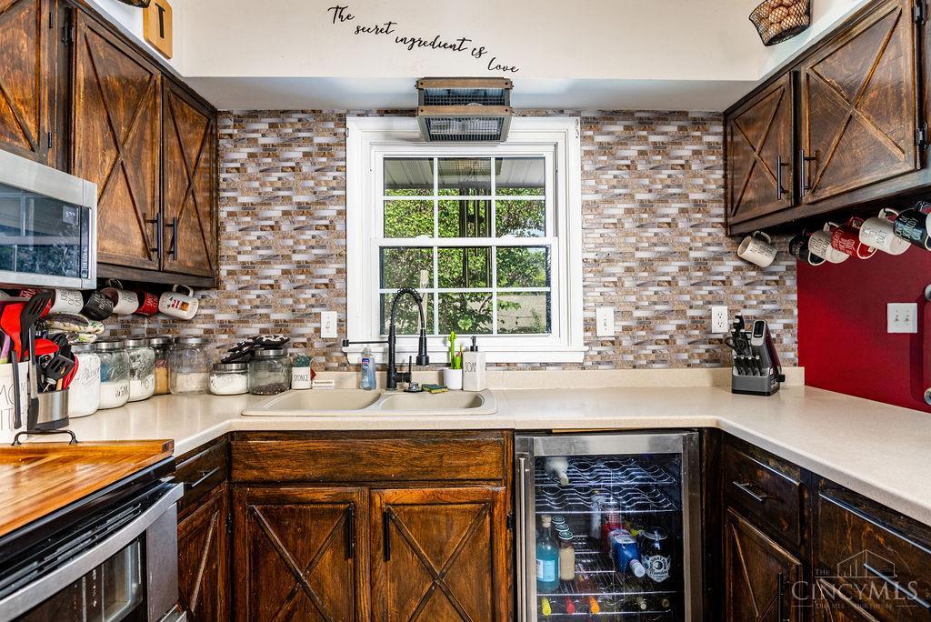 Kitchen with rustic wood cabinets, mosaic tile backsplash, and a sink beneath a window.