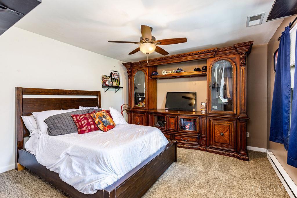 Bedroom with white bedding and an ornate wood entertainment center and television.