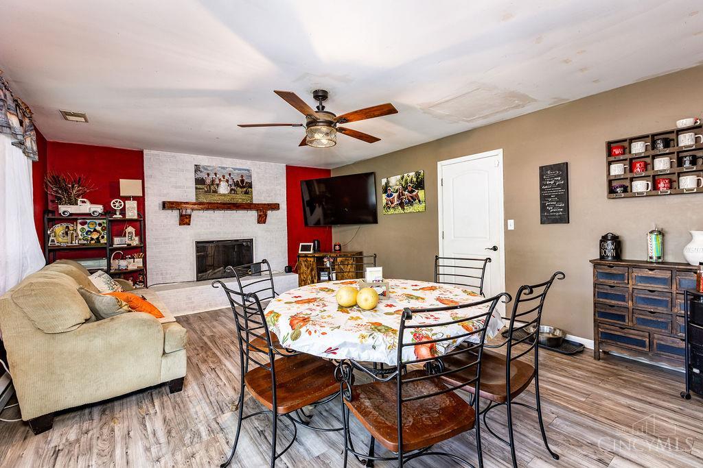 Living and dining room with a round floral-covered table, brick fireplace, and red accent wall.