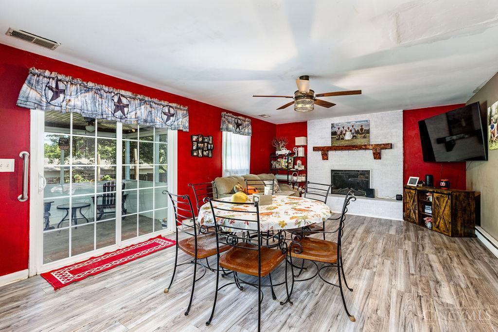 Dining and living room with a round table, red walls, fireplace, and sliding glass doors.