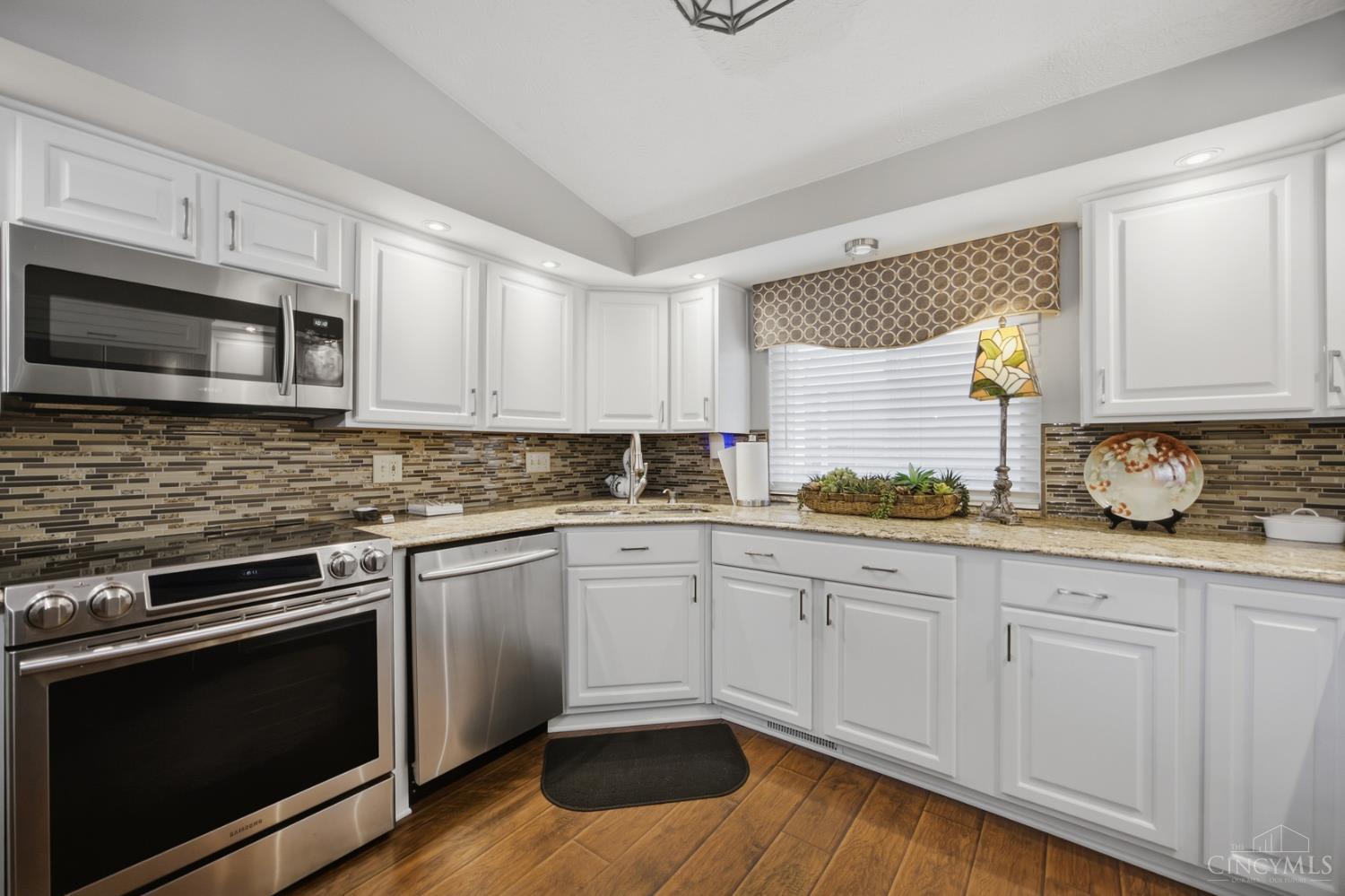 Kitchen with white cabinets, stainless steel appliances, and a brown mosaic tile backsplash.
