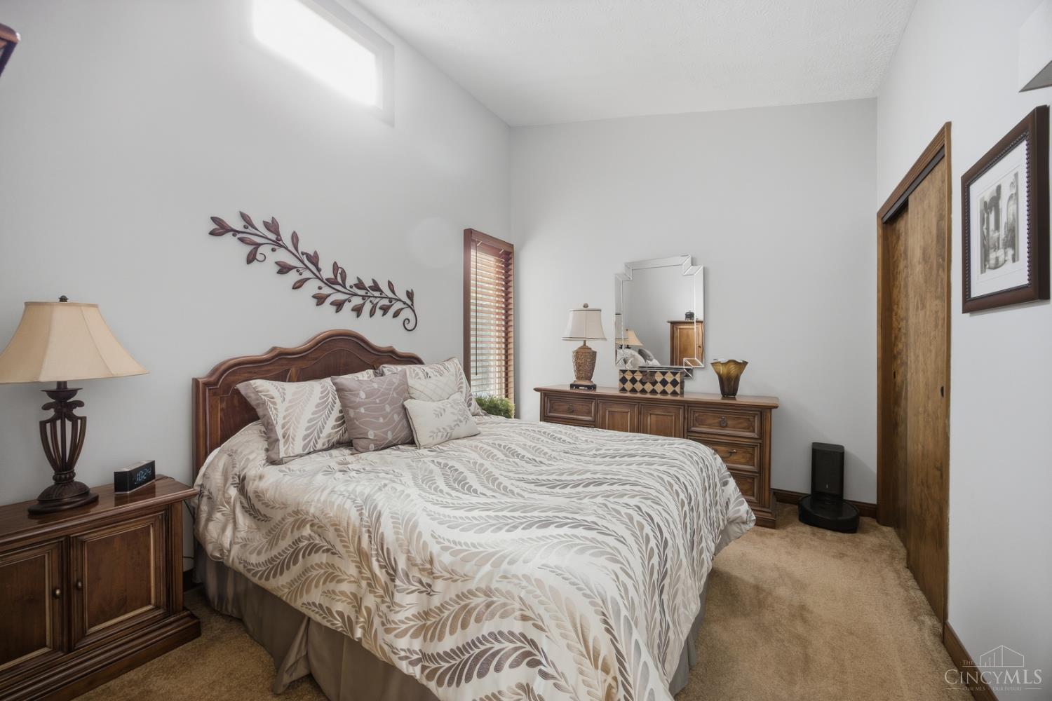 Bedroom with a wooden bed, leaf-patterned bedding, and matching dressers.