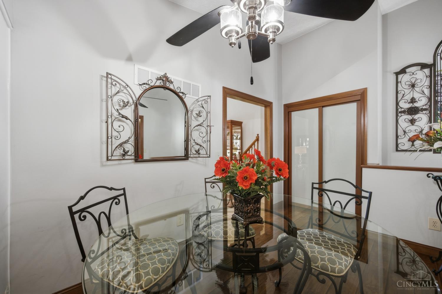 Dining room with a glass-top table, wrought-iron chairs, and an ornate arched mirror.