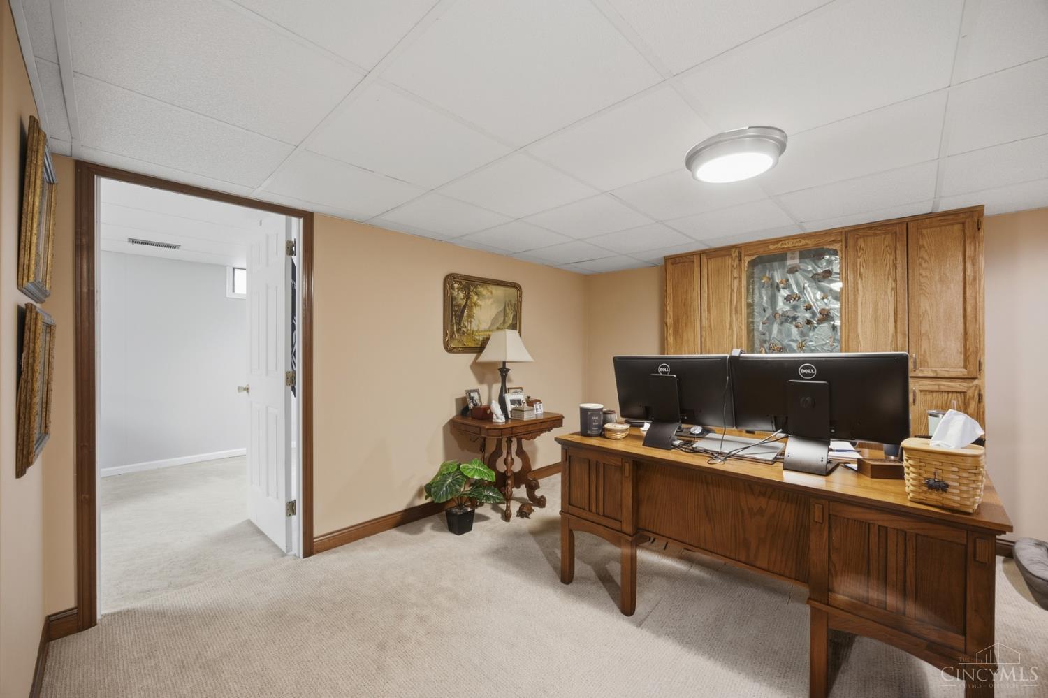 Furnished home office with a wooden desk, dual monitors, and built-in cabinets.