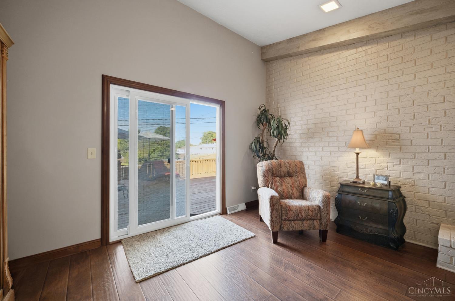 Living room with a white brick accent wall and sliding glass doors to a deck.