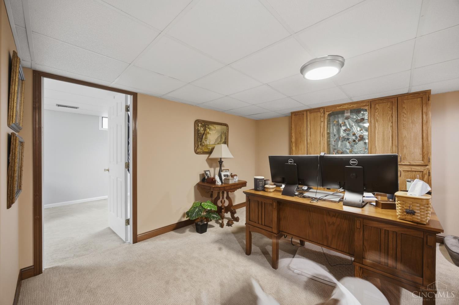 Home office with a large wooden desk, dual monitors, and built-in cabinets.
