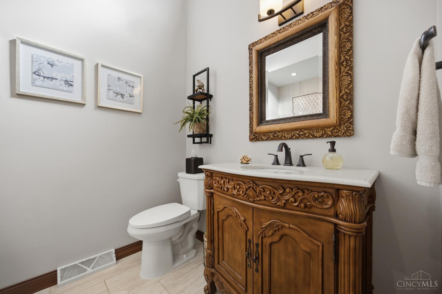 Bathroom with an ornate carved wood vanity, framed mirror, and white toilet.