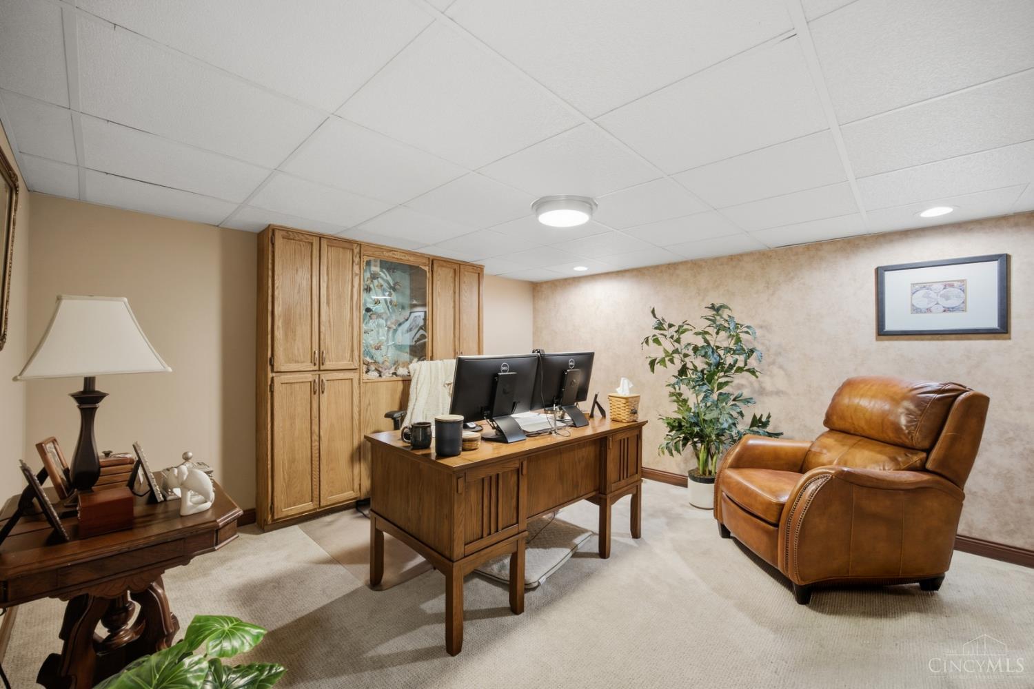 Furnished home office with built-in cabinets, a wooden desk, and a brown leather recliner.