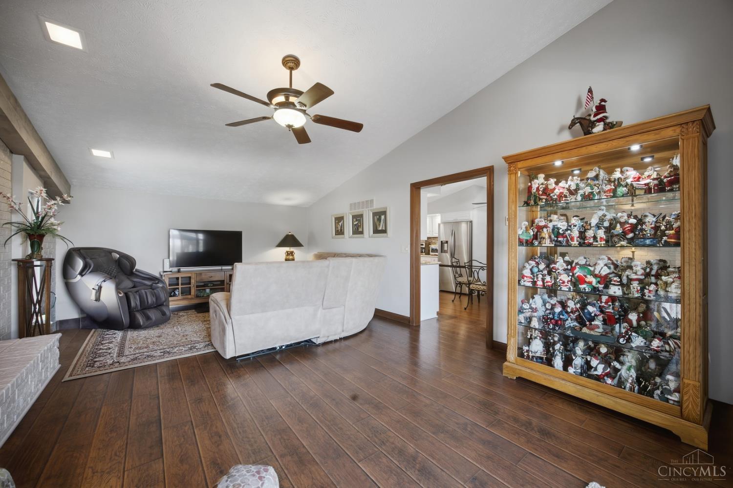 Living room with a Santa figurine collection, massage chair, and wood-look floors.
