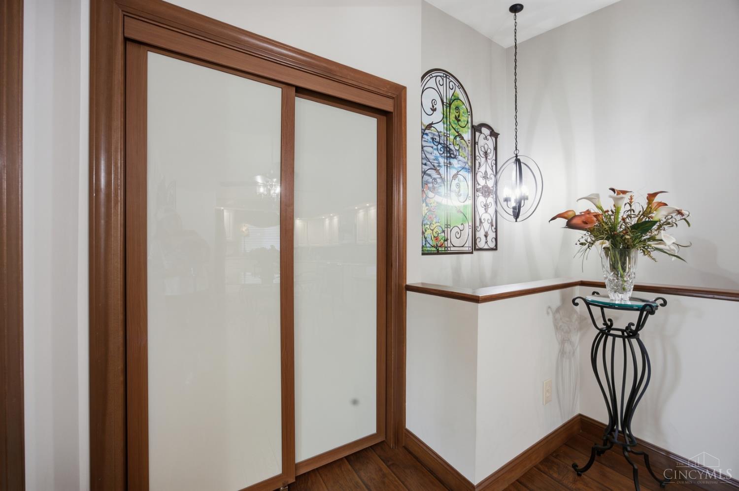 Entryway with wood-framed frosted-glass doors, dark wood trim, and a flower arrangement on a console table.