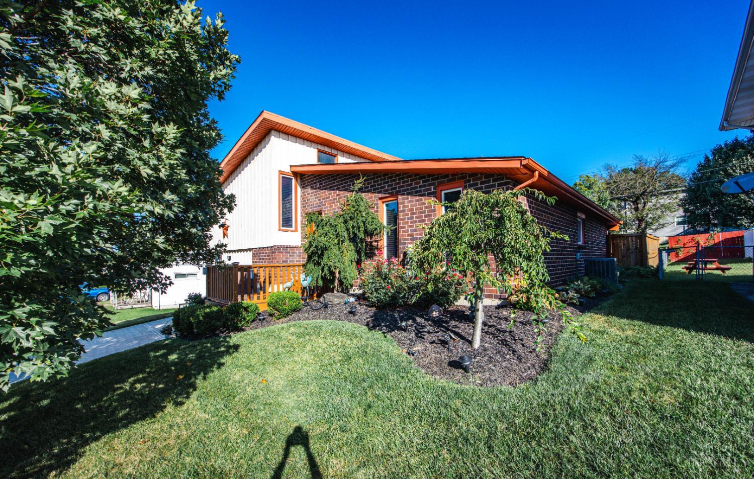 Two-story brick-and-siding home with a wooden deck and landscaped lawn.