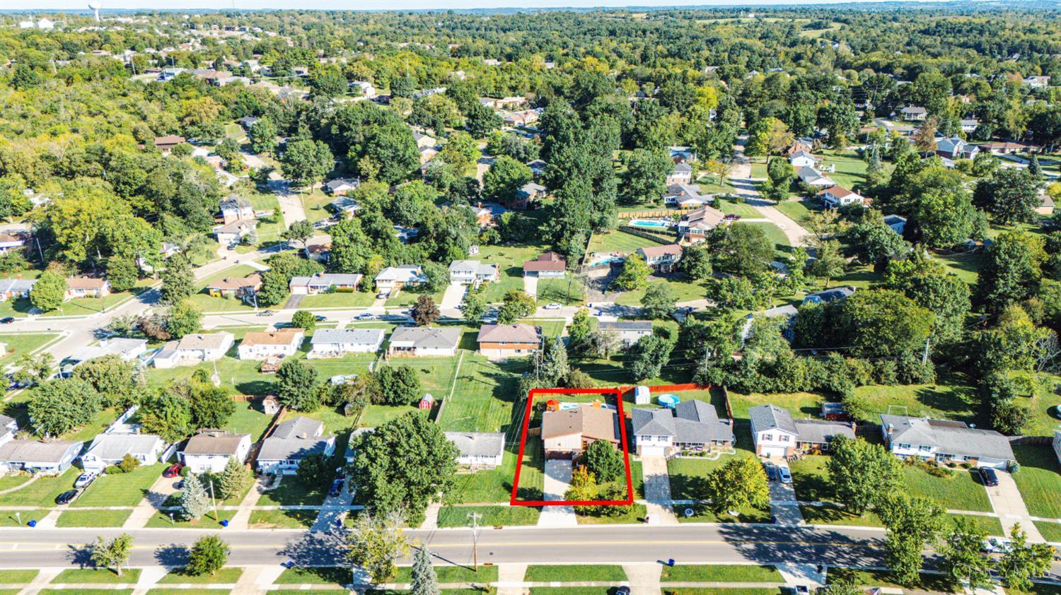 Aerial view of a home and its red-outlined lot beside a residential street.