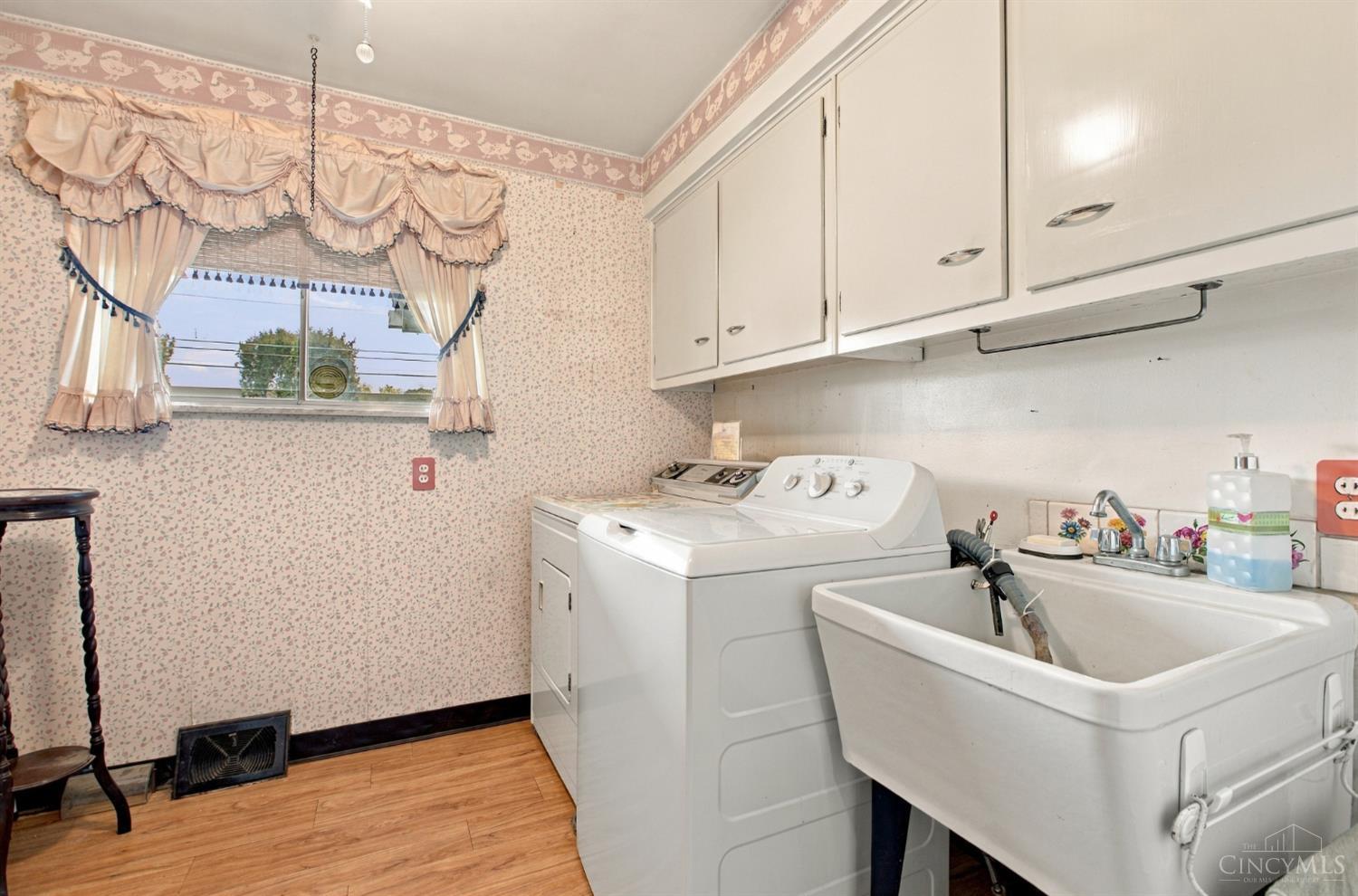 Laundry room with washer, dryer, deep utility sink, and upper cabinets.