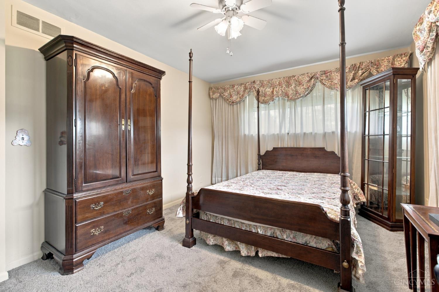 Bedroom with a dark wood four-poster bed, matching armoire, and floral bedding.