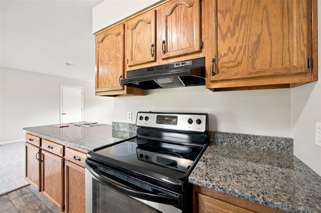 Kitchen with wood cabinets, granite counters, and a black electric range.