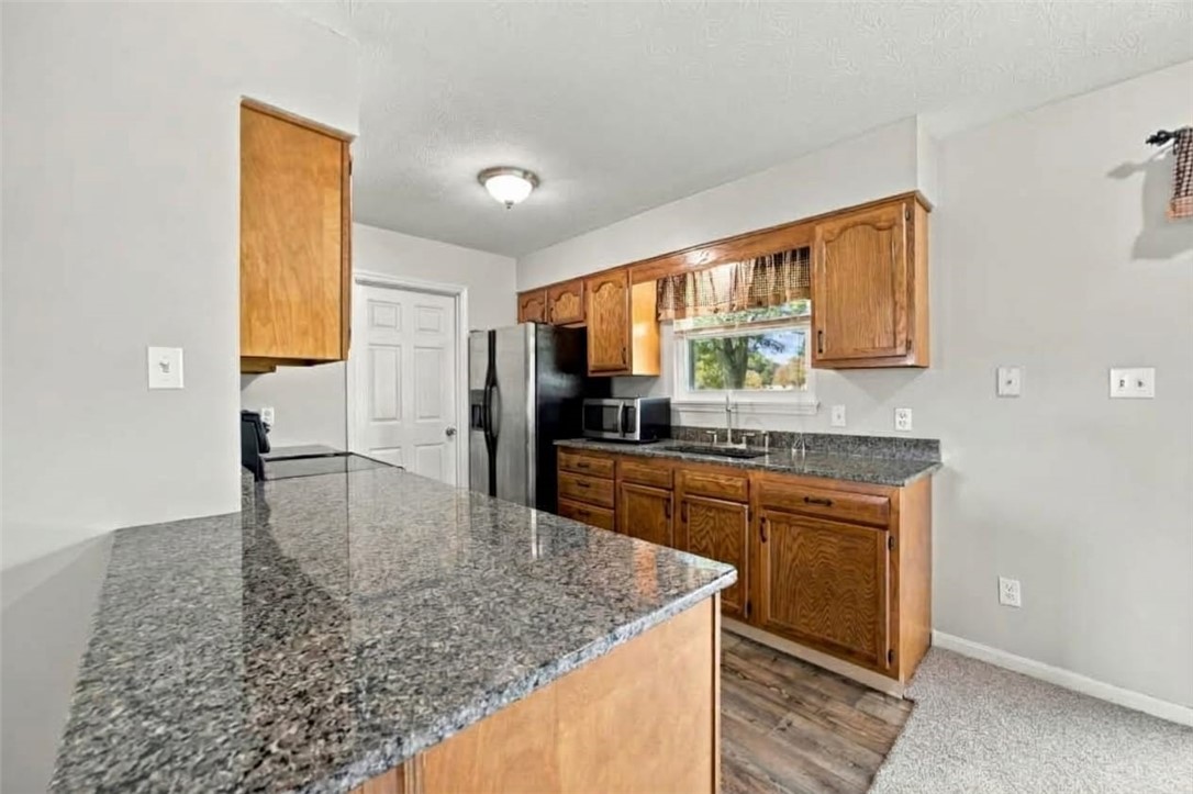Kitchen with wood cabinets, gray granite counters, and a large peninsula.