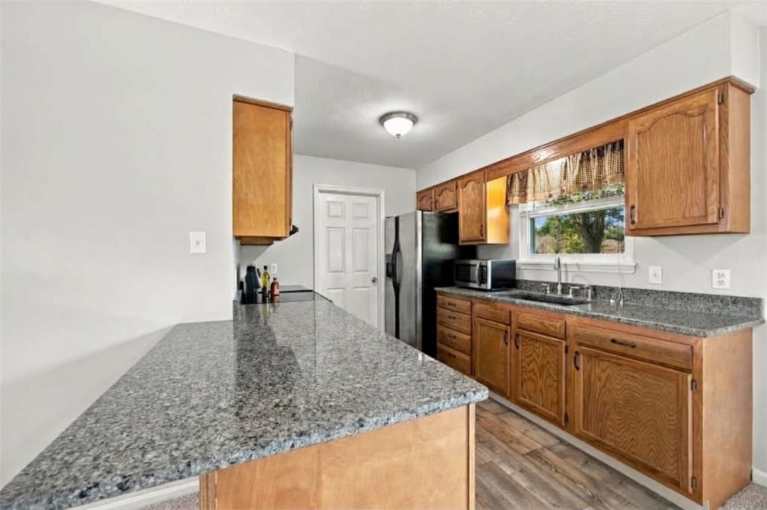 Kitchen with wood cabinets, granite counters, a large peninsula, and a window above the sink.