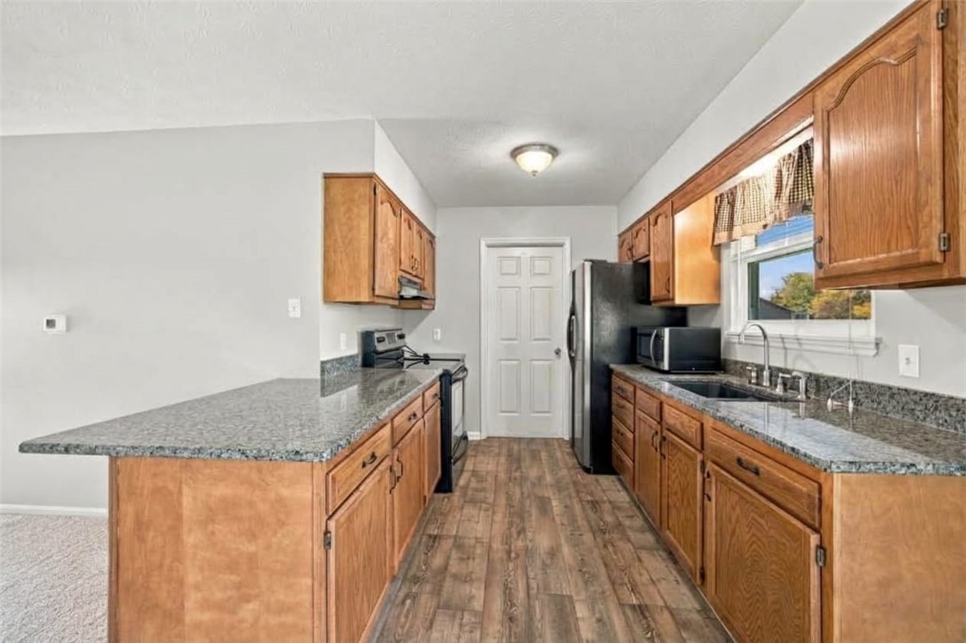 Kitchen with wood cabinets, gray countertops, a central island, and a window above the sink.