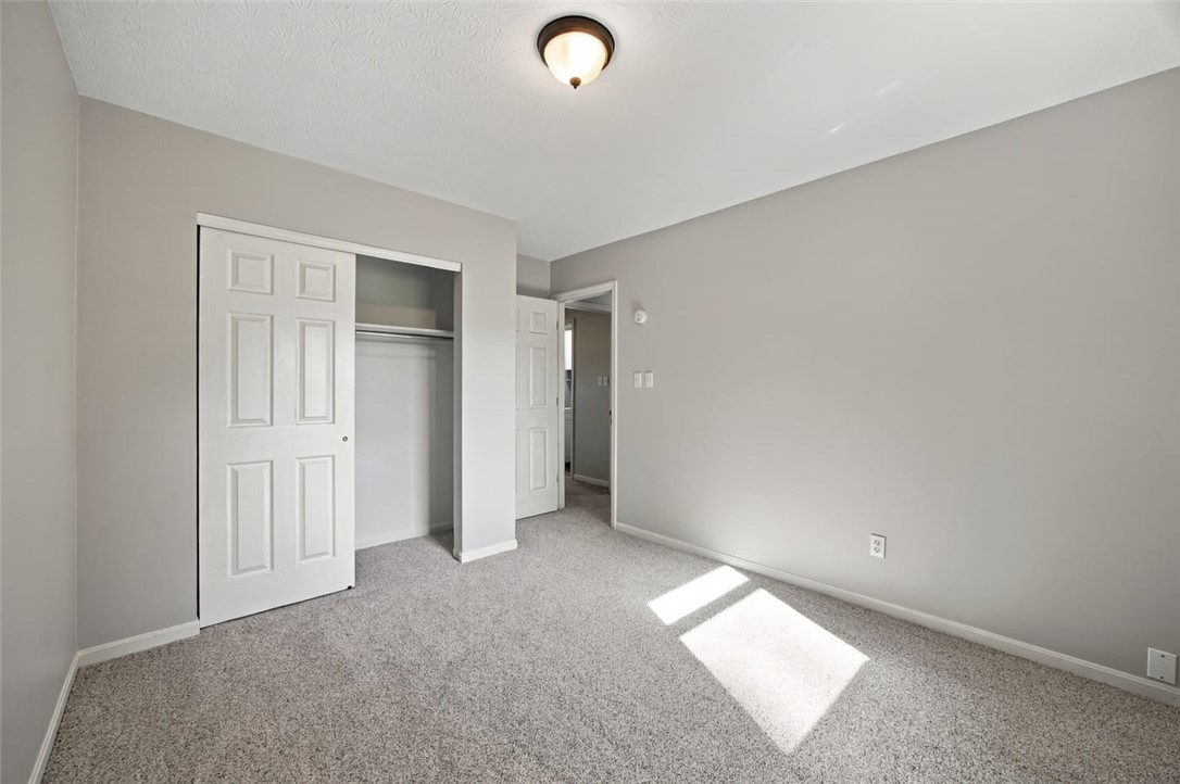 Empty bedroom with a sliding-door closet and sunlight on the carpet.