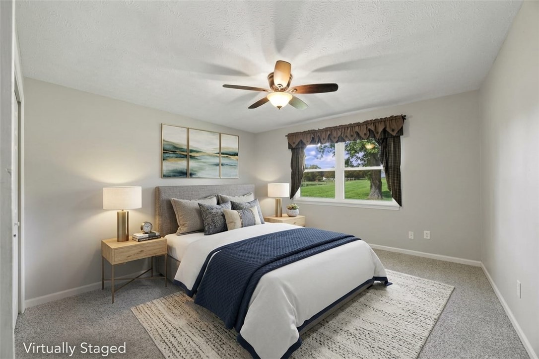 Virtually staged bedroom with a navy-and-white bed, ceiling fan, and window overlooking a lawn.