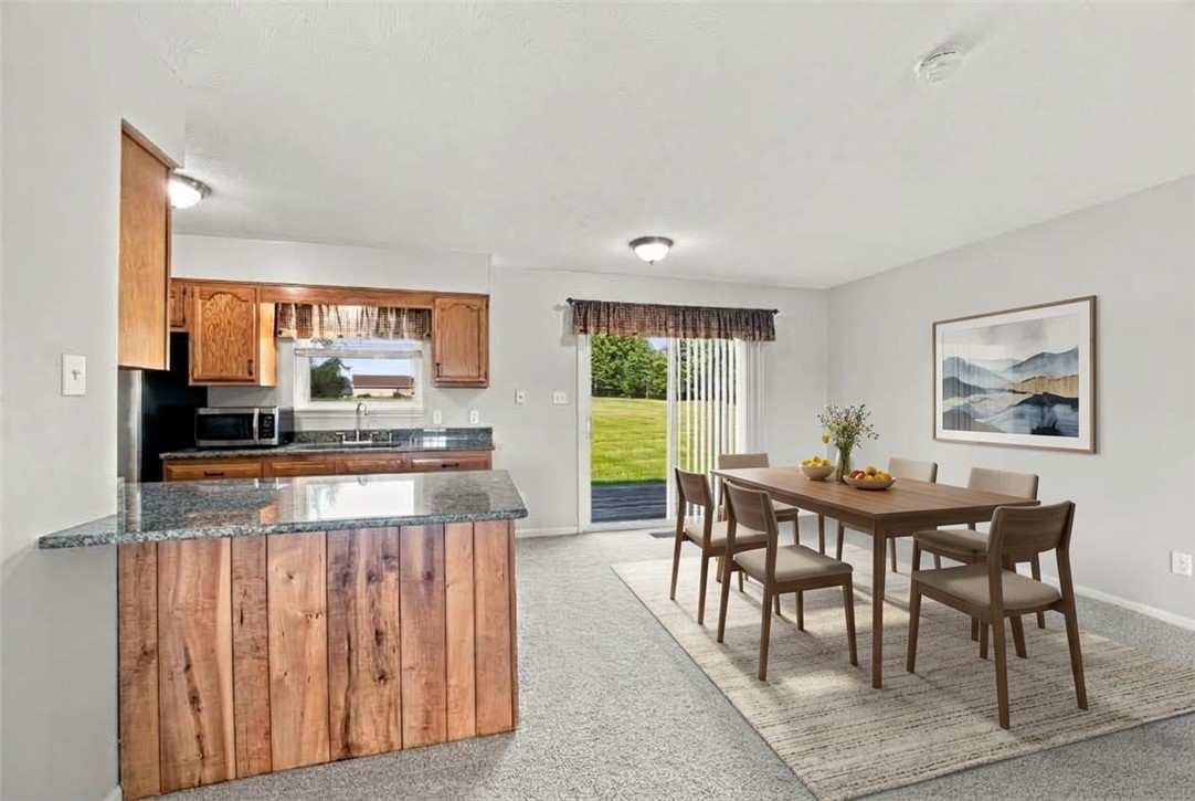 Kitchen and dining area with a granite peninsula, wood cabinets, and sliding doors to the lawn.