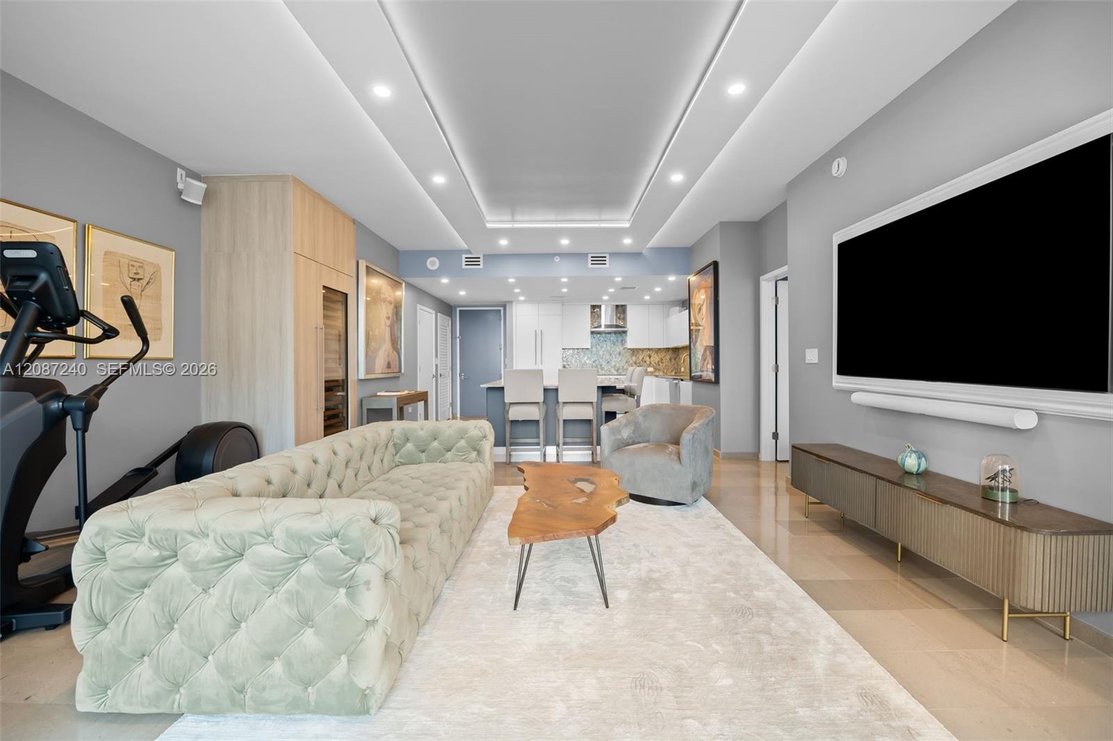 Furnished condo living room with a mint tufted sofa and open kitchen.