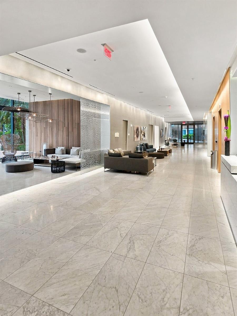 Modern condominium lobby with polished marble floors and a wood-paneled lounge seating area.