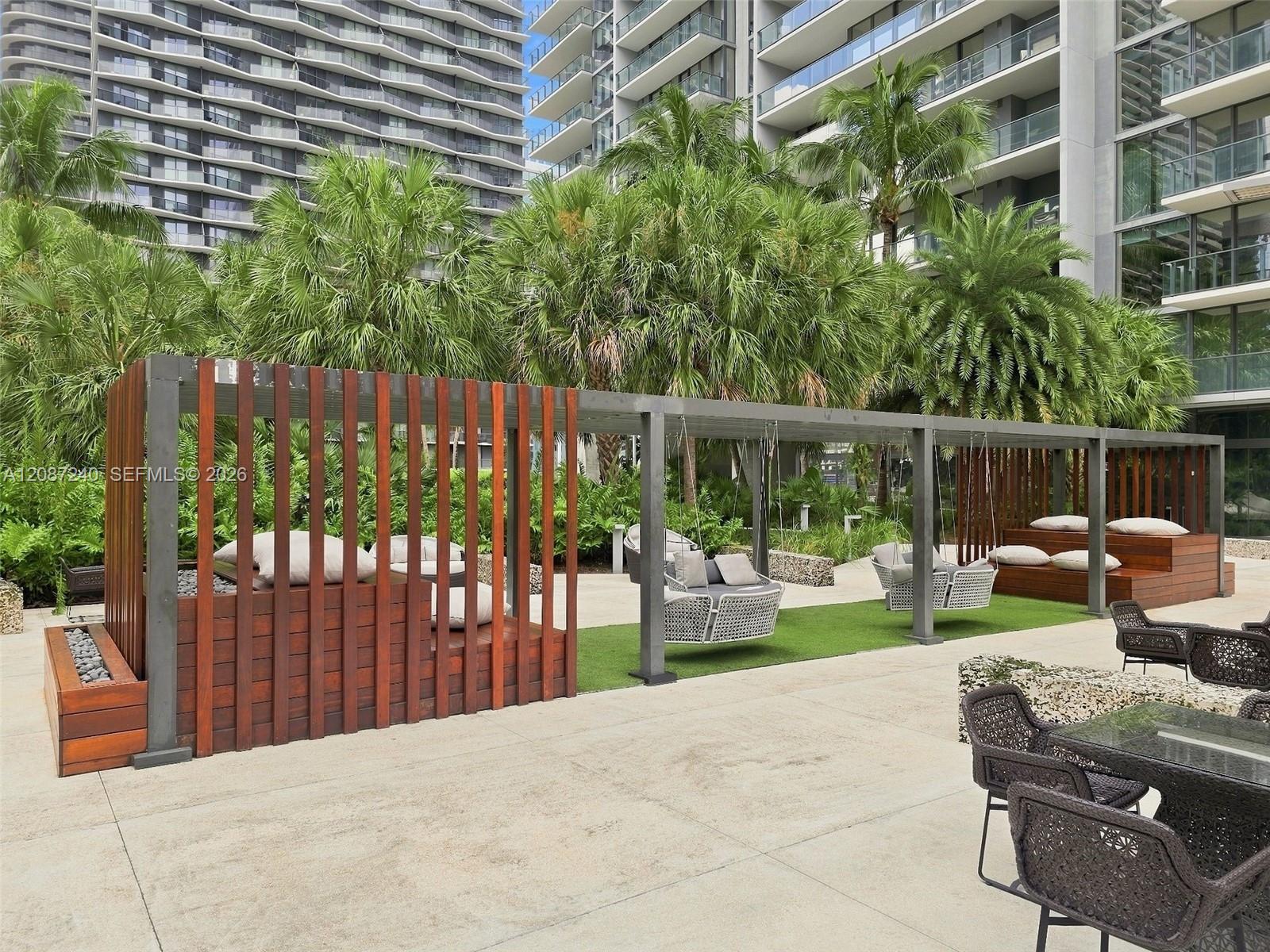 Condominium courtyard with tropical landscaping, wood-screened lounge seating, and a paved patio.