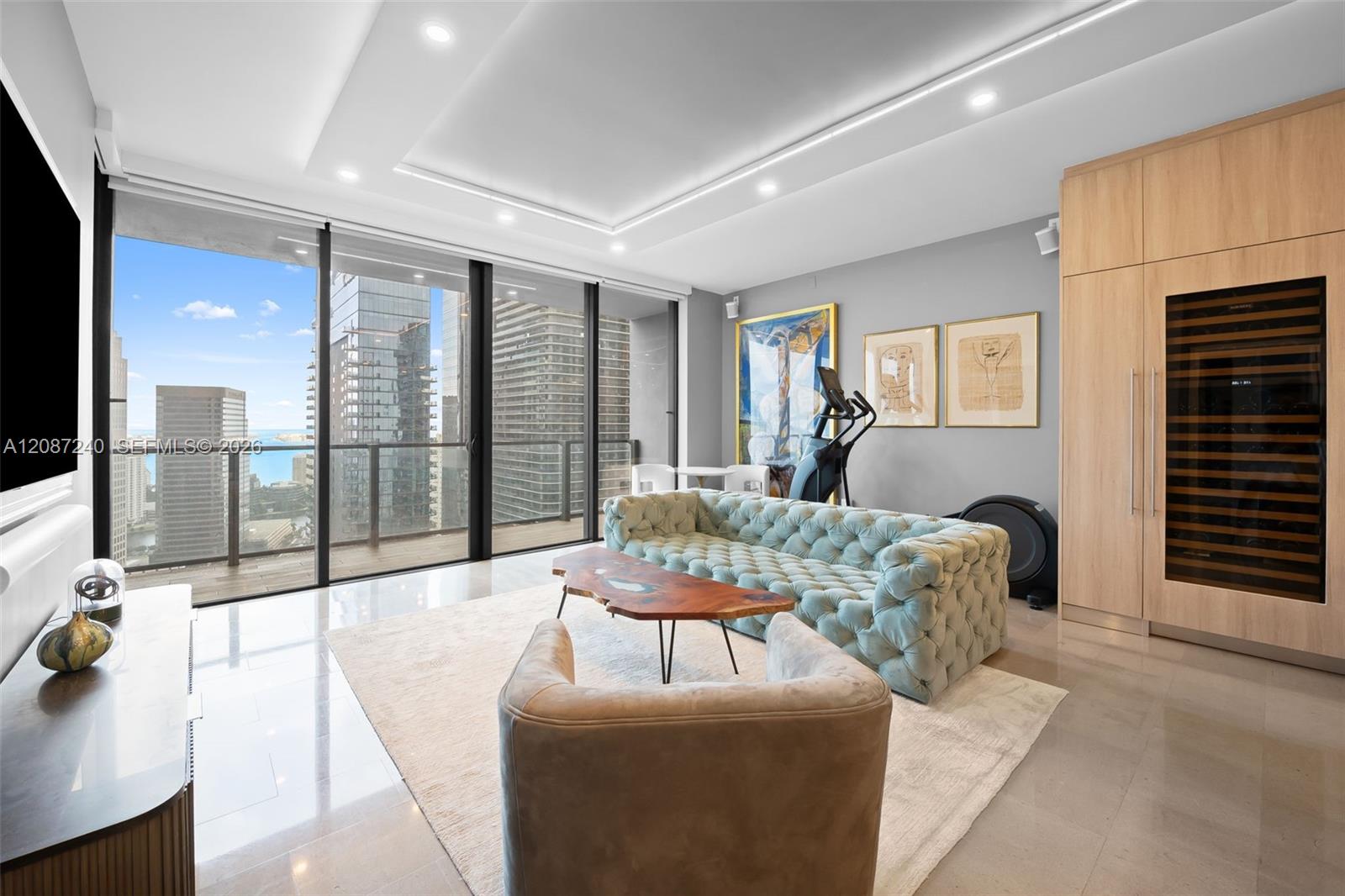 High-rise living room with a pale blue tufted sofa and city and water views through floor-to-ceiling windows.
