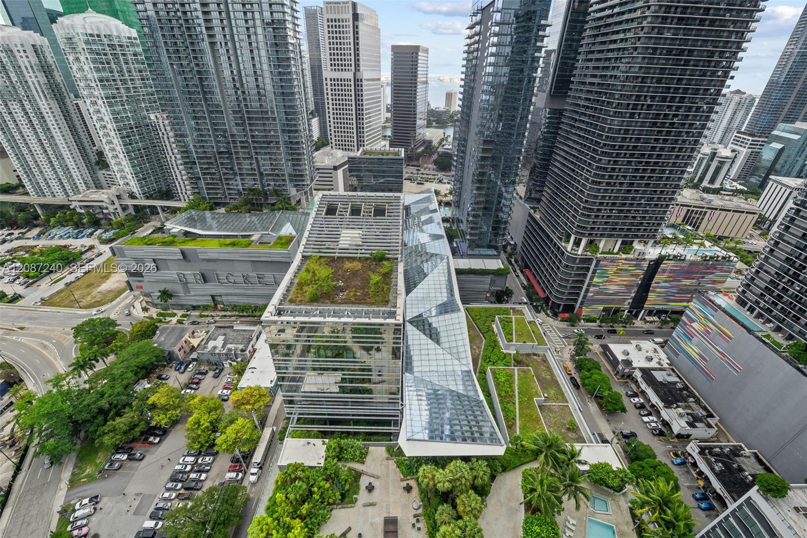 Aerial view of downtown Miami high-rises, rooftop gardens, streets, and pools.