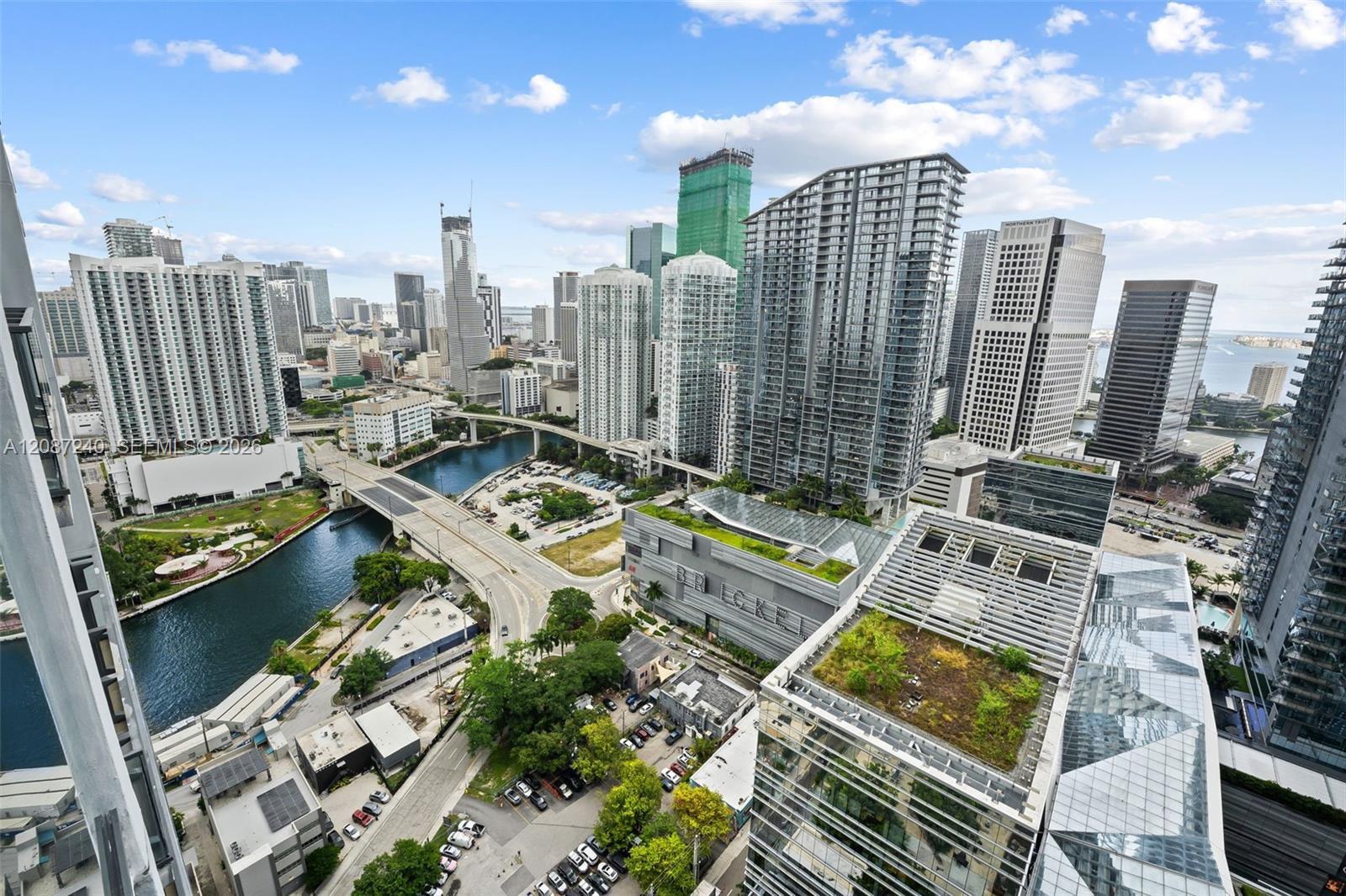 Downtown Miami skyline and waterways viewed from a high-rise, with bridges and rooftop terraces.