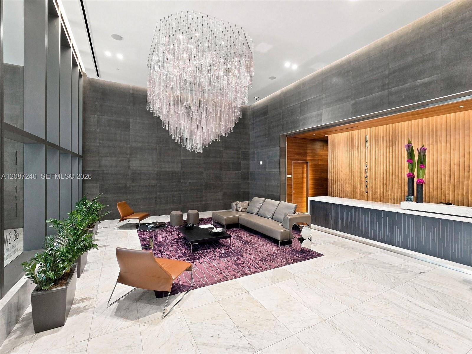 Condominium lobby with a dramatic crystal chandelier and wood-paneled reception desk.