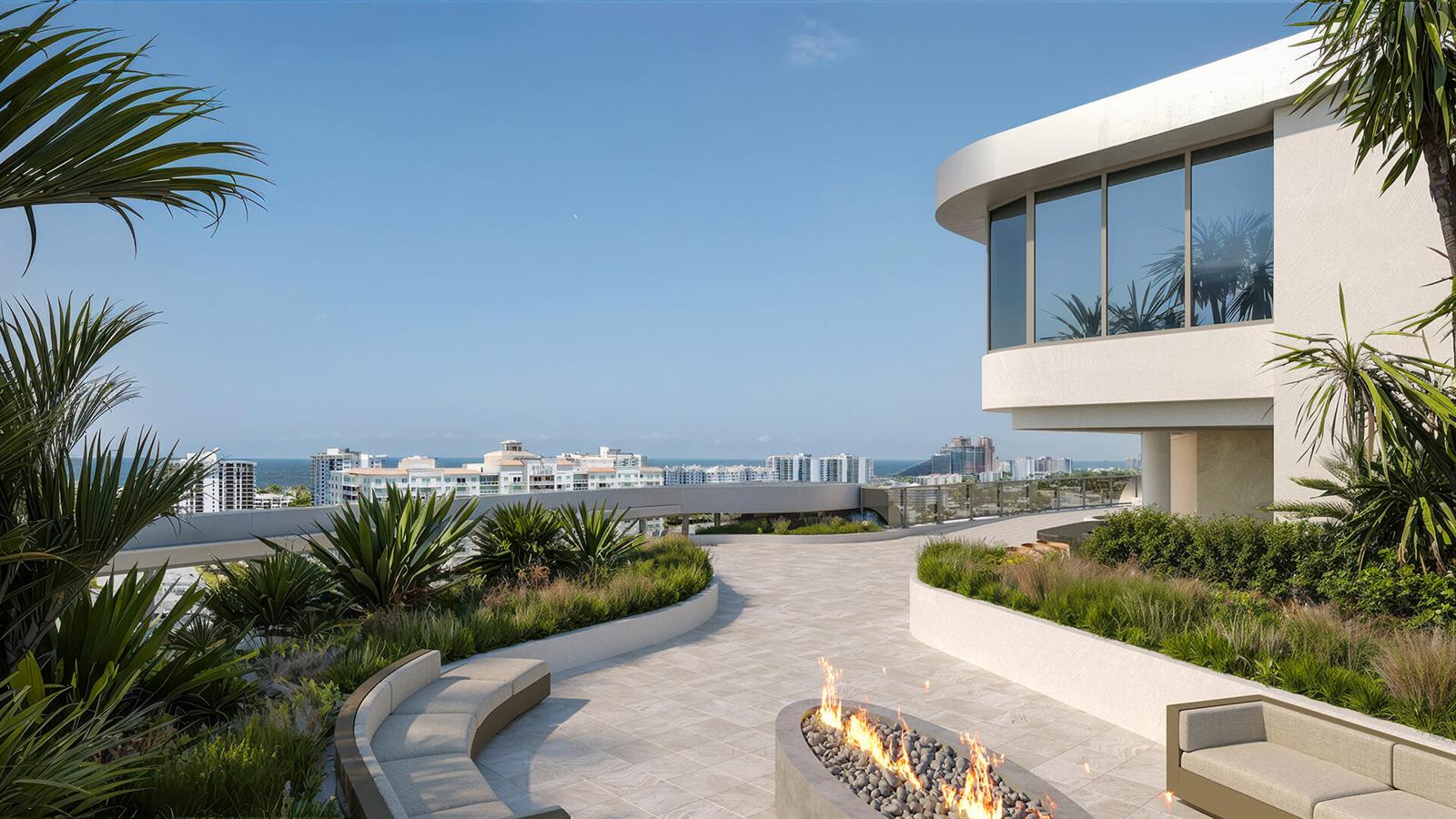 Rooftop terrace with curved seating and a fire pit overlooking the coastal skyline and ocean.