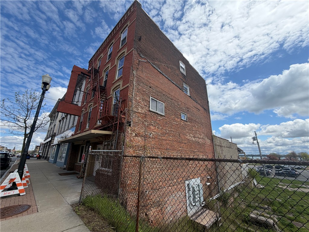Multi-story brick building beside a fenced lot on a downtown sidewalk.