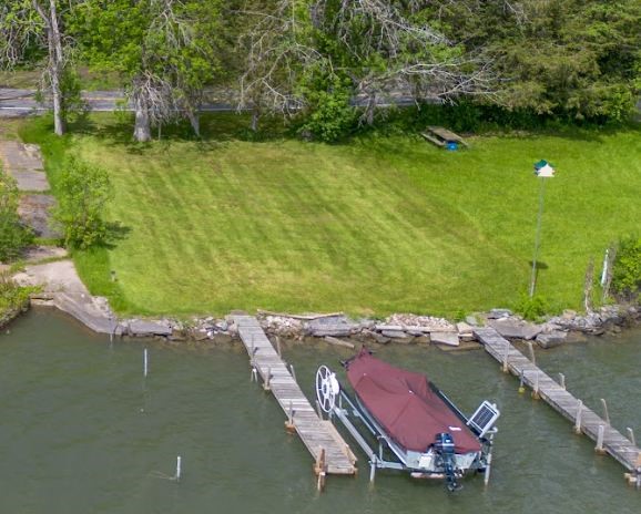 Waterfront property with a broad grassy lawn, several docks, and a boat moored at the shore.