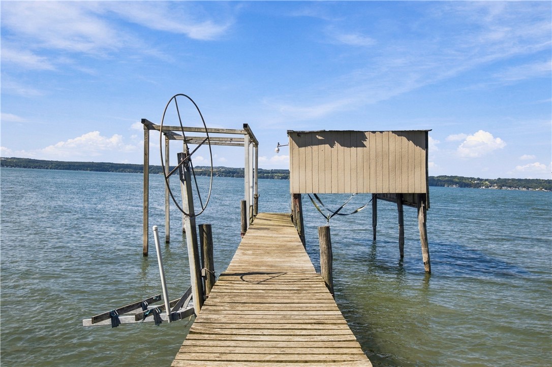Wooden dock and raised boathouse extending into a lake, with a metal wheel lift structure.