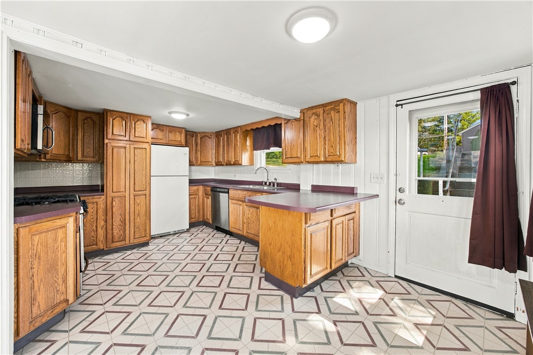 Kitchen with honey-colored cabinets, maroon countertops, a central island, and geometric patterned flooring.