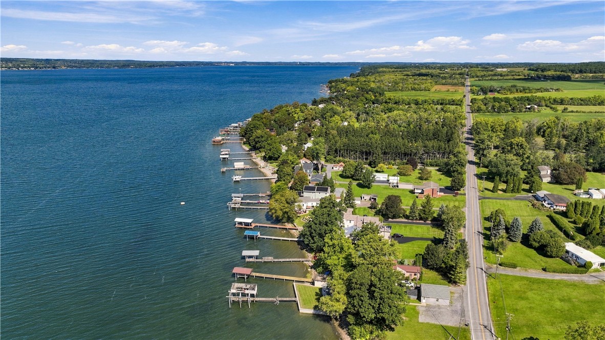 Aerial view of lakeside homes and docks lining the shore beside a long road.