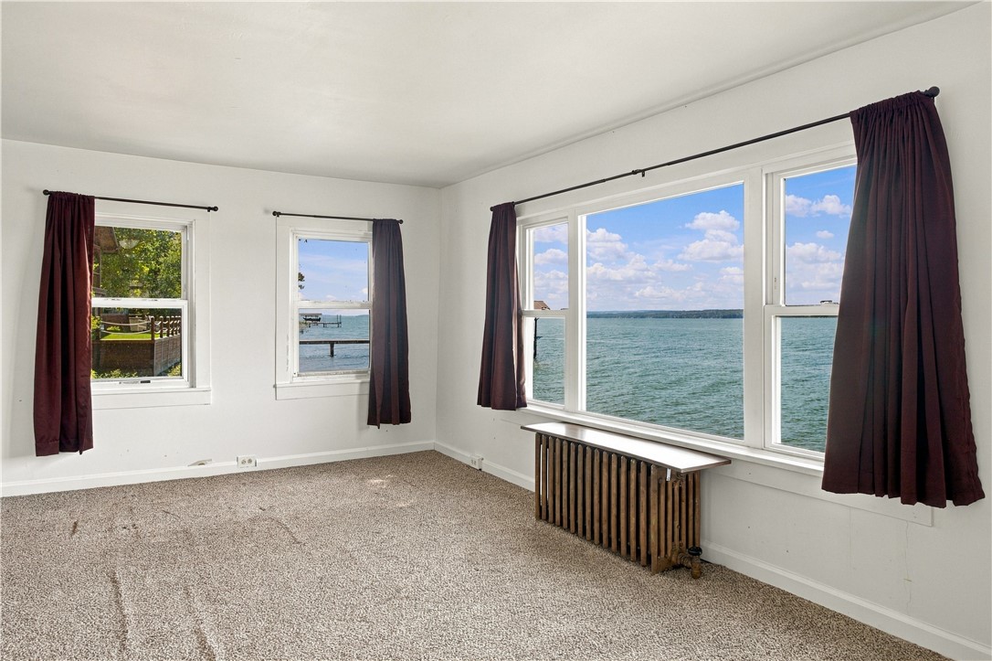 Unfurnished room with burgundy curtains and large windows overlooking the lake.