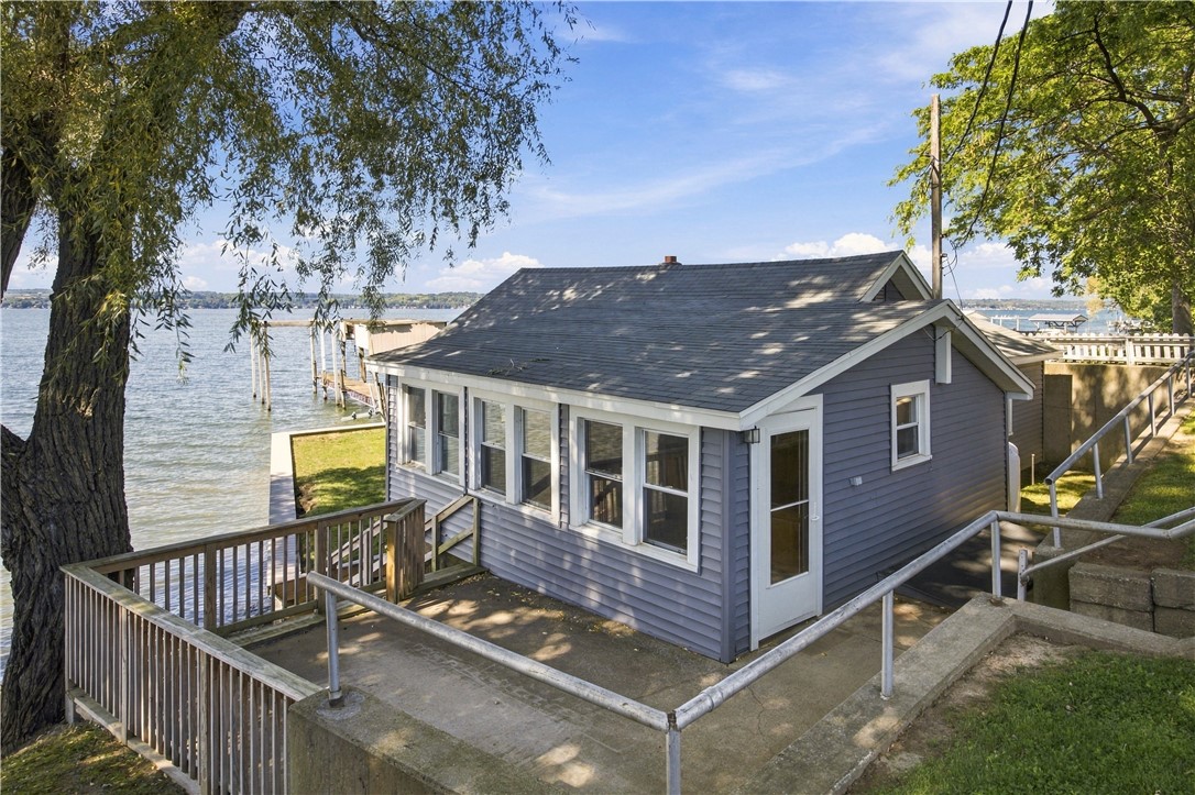 Lakefront cottage with a waterside deck and a row of large windows.
