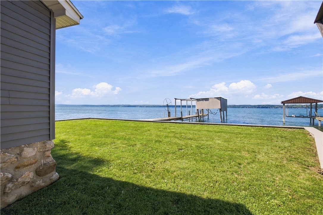 Waterfront lawn with two docks extending into the lake beside a gray-sided house.