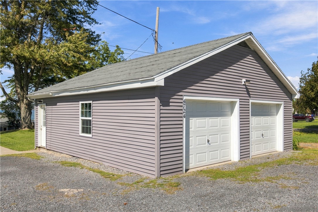 Detached two-bay garage with mauve siding, white doors, and a gravel driveway.