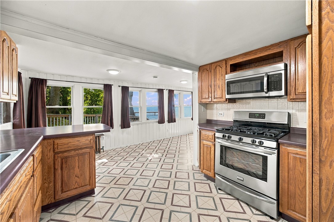 Kitchen with wood cabinets, stainless steel appliances, geometric tile flooring, and lake views through the windows.